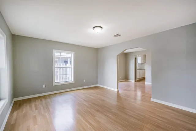 an empty room with wooden floor and windows
