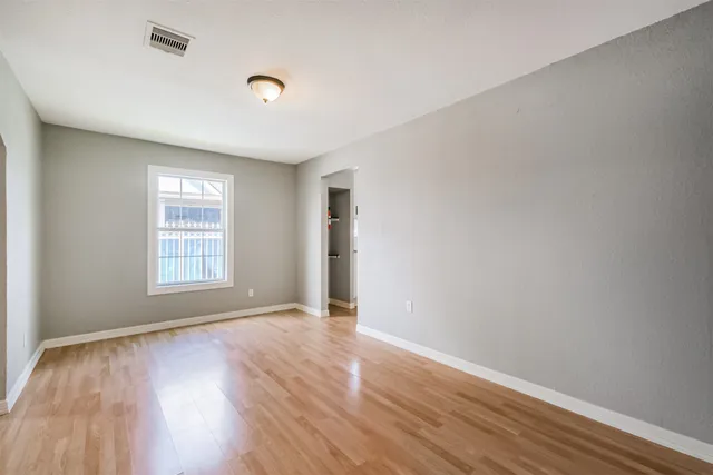 a view of an empty room with wooden floor and a window