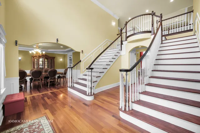 a dining room with wooden floor a chandelier a glass table and chairs