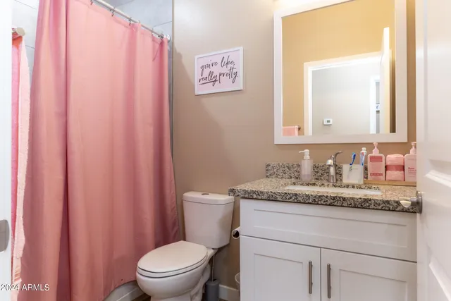 a bathroom with a granite countertop sink mirror vanity and toilet