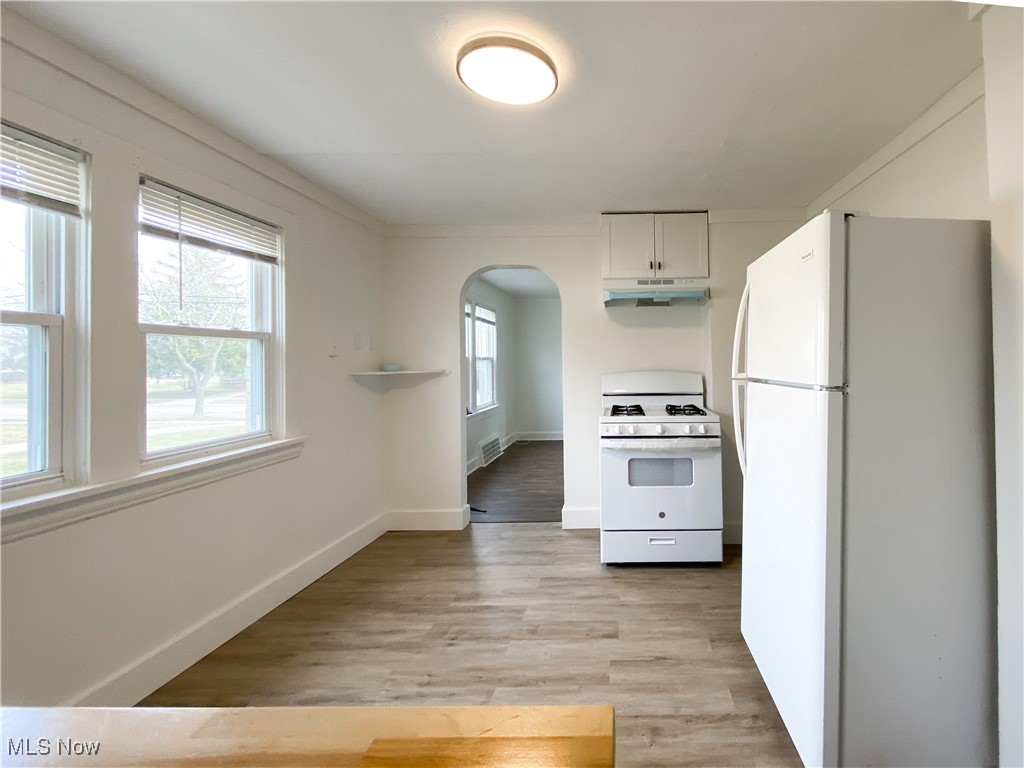 14628 Granger Road Maple Heights, OH 44137 - Photo 6 of 45 Kitchen with white appliances, white cabinets, and light hardwood / wood-style flooring