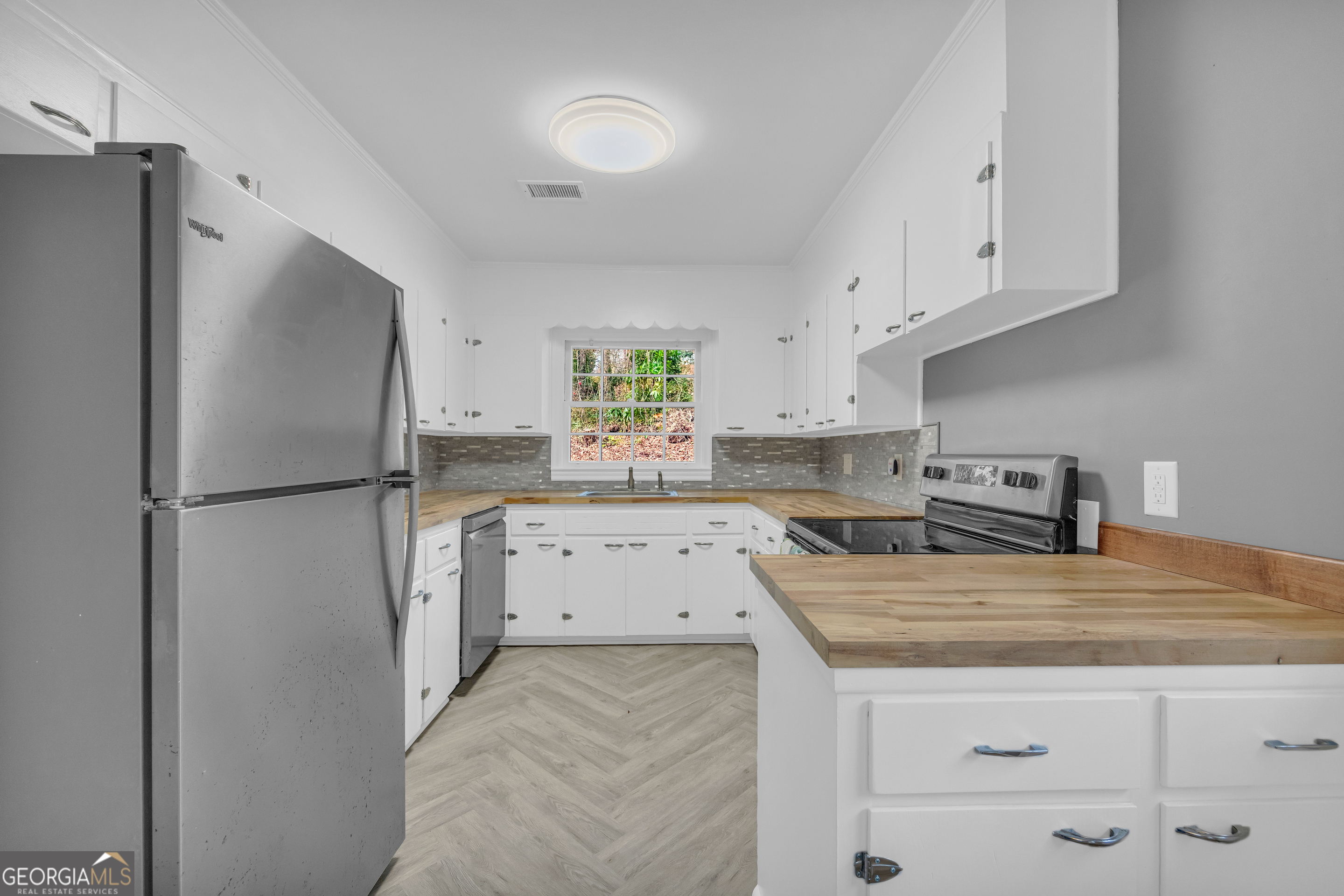 998 Rosedale Street Toccoa, GA 30577 - Photo 7 of 43 a kitchen with a refrigerator a stove a sink and white cabinets