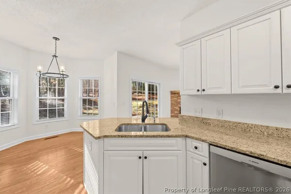 a kitchen with stainless steel appliances granite countertop a sink a stove and white cabinets