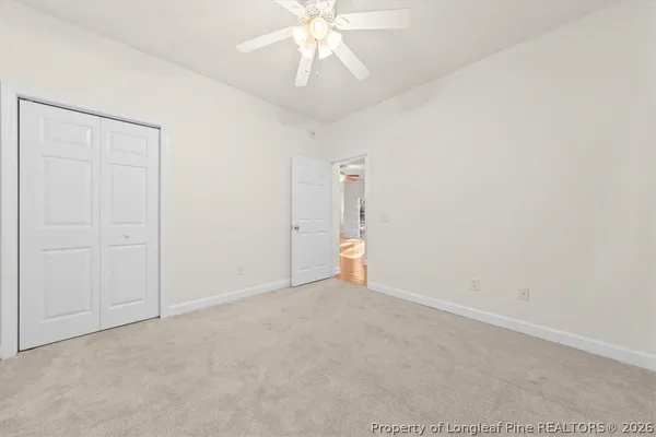 an empty room with chandelier fan and entryway