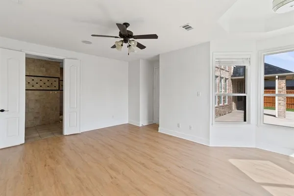 a view of an empty room with a window and wooden floor