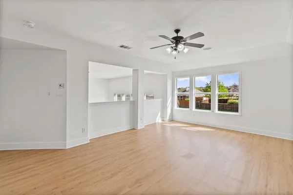 a view of an empty room with window and wooden floor