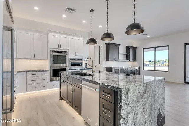 a kitchen with granite countertop white cabinets and stainless steel appliances