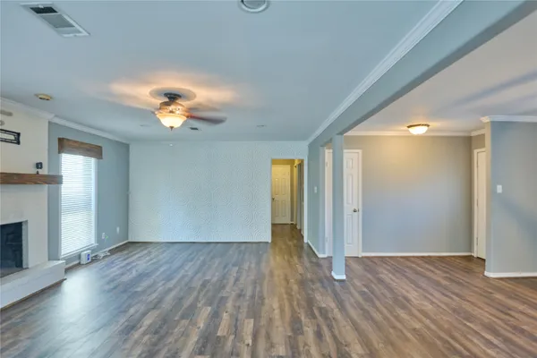 a view of an empty room with window and wooden floor