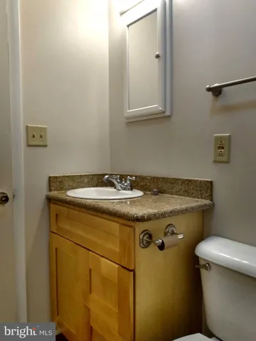 a bathroom with a granite countertop sink and a toilet
