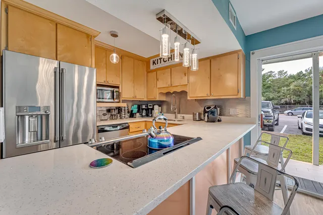 a kitchen with stainless steel appliances a sink a stove a refrigerator cabinets and a dining table