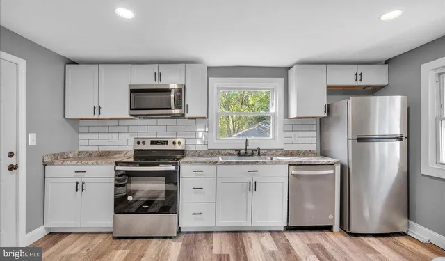 a kitchen with cabinets stainless steel appliances and a window