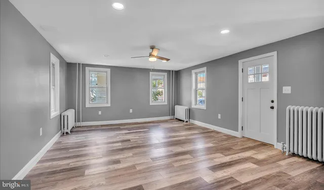 a view of an empty room with window and wooden floor