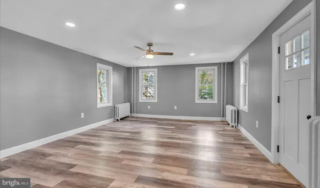 a view of an empty room with wooden floor and a window