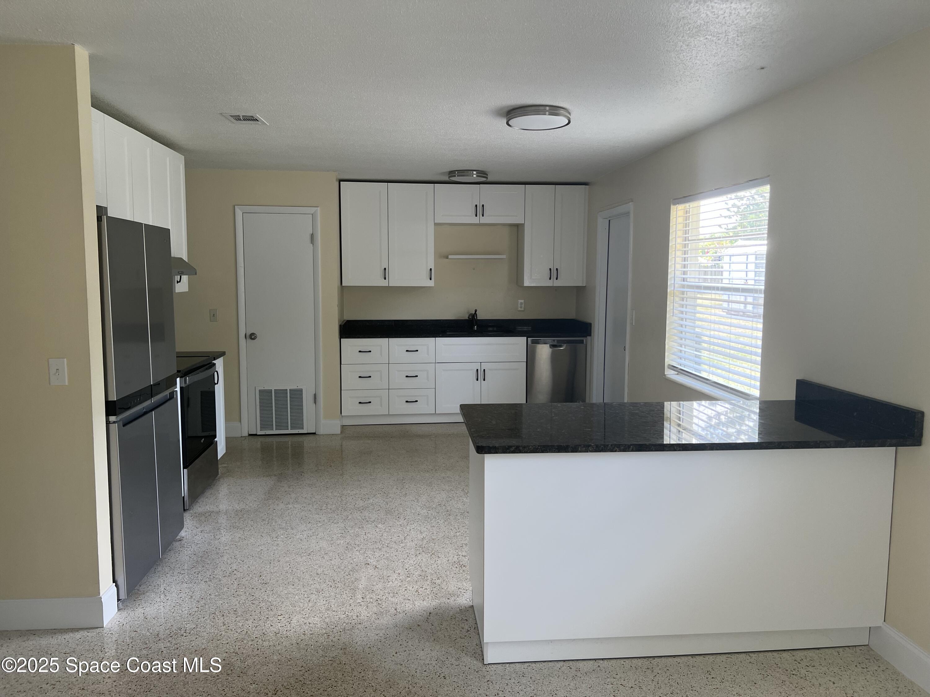2906 Rollins Street Melbourne, FL 32901 - Photo 4 of 12 a kitchen with stainless steel appliances a refrigerator sink and stove