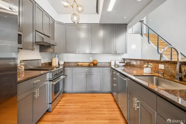 a kitchen with stainless steel appliances granite countertop a sink a stove and a wooden floors