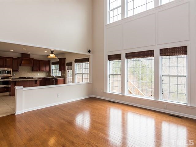 209 Amiable Loop Cary, NC 27519 - Photo 5 of 25 a view of an empty room with wooden floor and a kitchen
