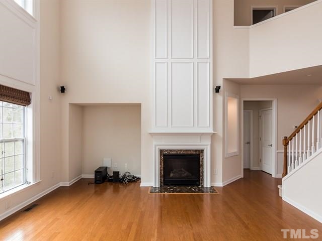209 Amiable Loop Cary, NC 27519 - Photo 6 of 25 an empty room with wooden floor a fireplace and windows