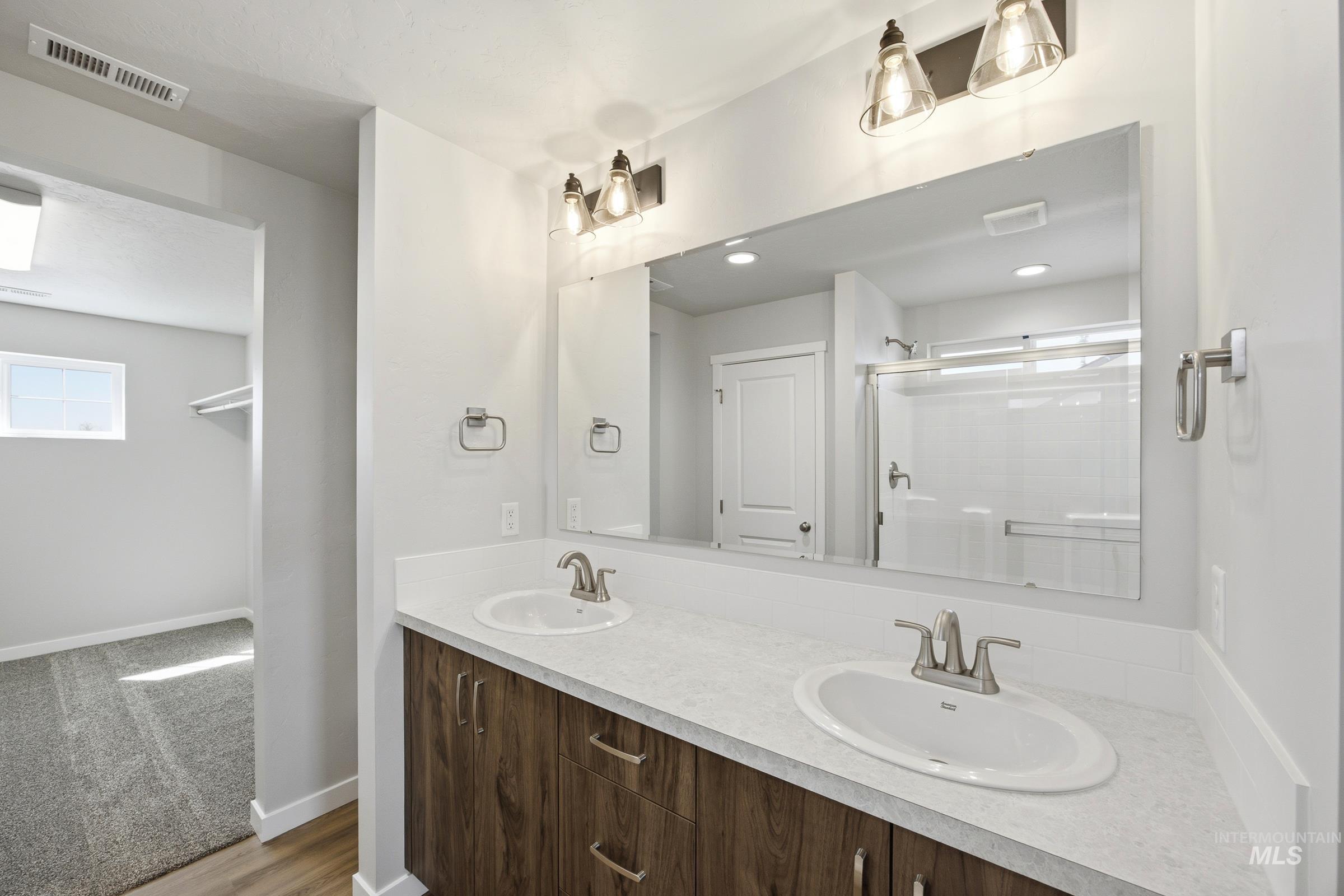 13333 Bank Street Caldwell, ID 83607 - Photo 21 of 29 Dual vanity with wood-finish cabinetry, light-toned countertops, and brushed nickel fixtures