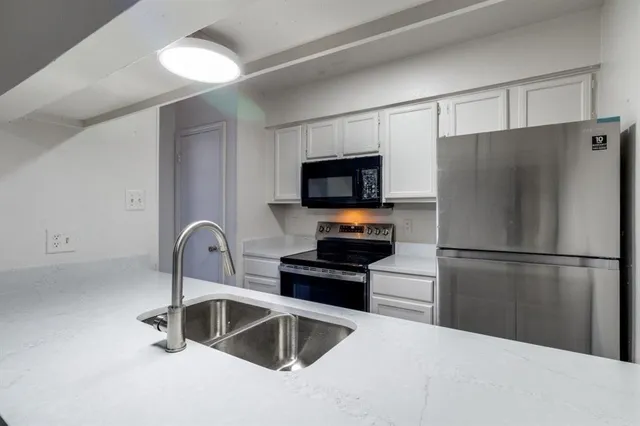 a kitchen with a refrigerator sink and white cabinets
