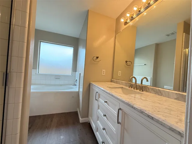 a bathroom with a granite countertop sink mirror and a bathtub