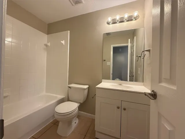 a bathroom with a toilet a sink a mirror a bathtub and vanity
