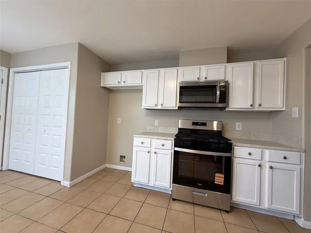 a kitchen with white cabinets and stainless steel appliances