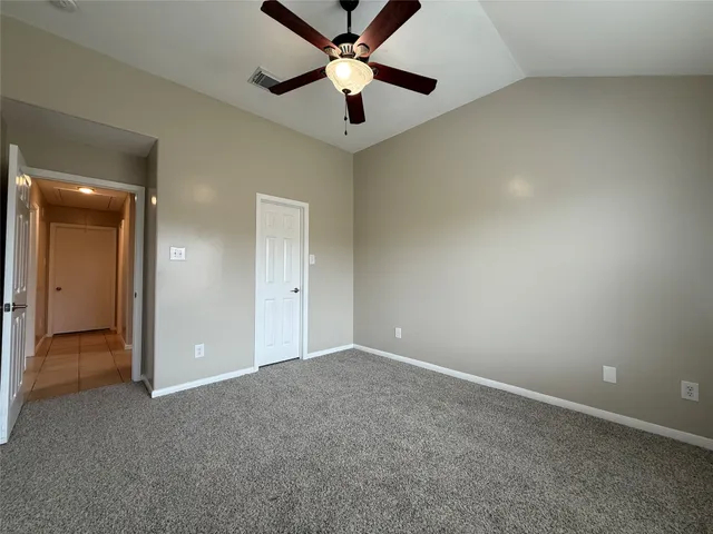an empty room with closet and a ceiling fan