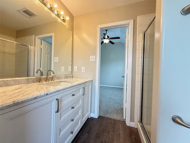 a bathroom with a granite countertop sink a mirror and a shower