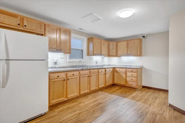 a kitchen with granite countertop a refrigerator a sink dishwasher a stove with wooden floors and cabinets