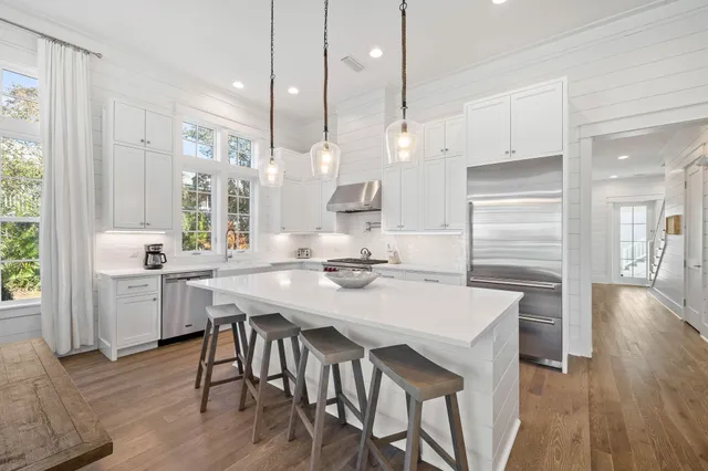 a view of a kitchen with wooden floor and white cabinets
