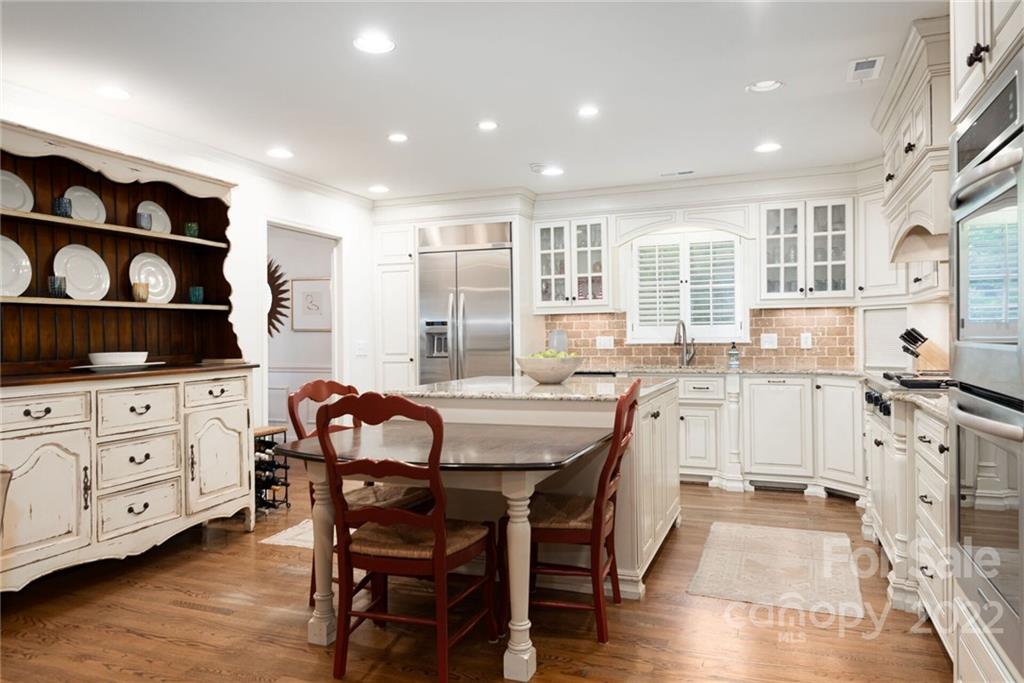 2815 Wickersham Road Charlotte, NC 28211 - Photo 9 of 34 a kitchen with stainless steel appliances kitchen island granite countertop a stove a sink a dining table and chairs with wooden floor