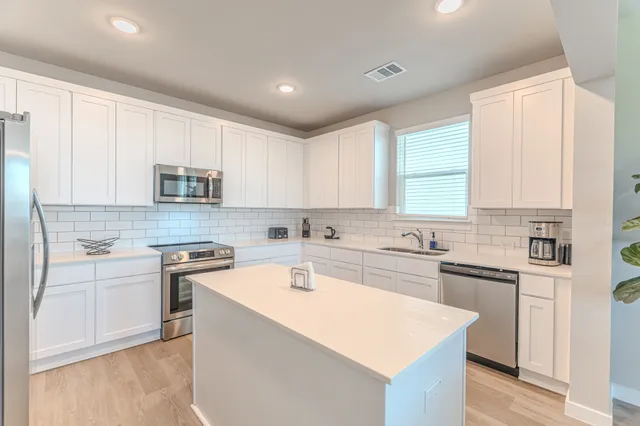 a kitchen with stainless steel appliances granite countertop white cabinets sink and stove