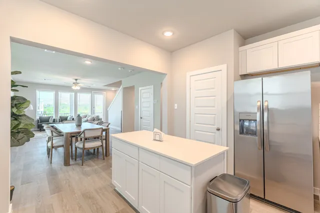 a room with a table chairs a refrigerator and cabinets