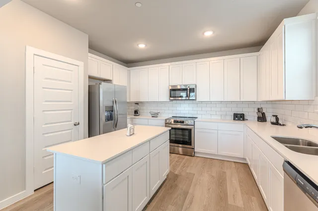 a kitchen with a sink a stove a refrigerator and white cabinets