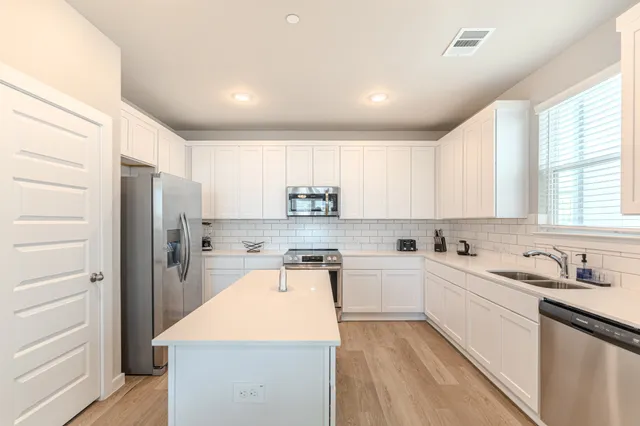 a kitchen with a sink a stove a refrigerator and white cabinets