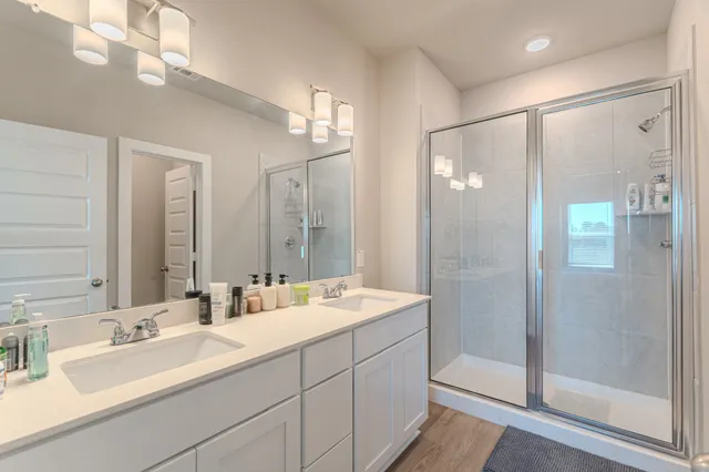 a bathroom with a double vanity sink mirror and shower
