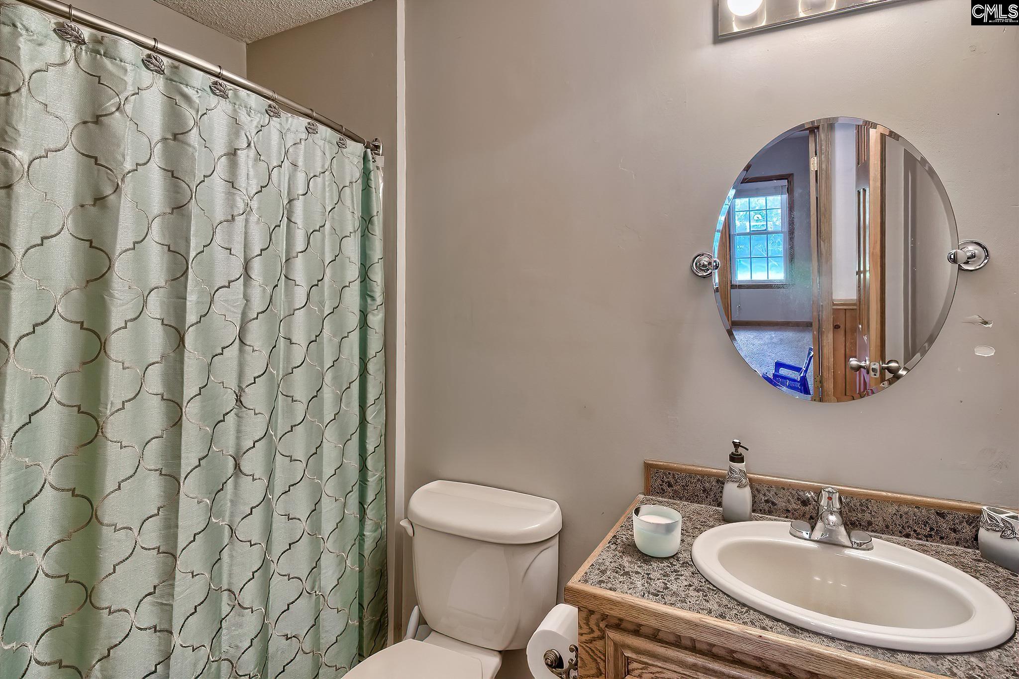 1415 State Rd S-28-55 Lugoff, SC 29078 - Photo 25 of 39 a bathroom with a toilet a sink and a mirror