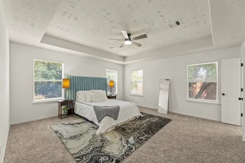 a spacious bedroom with a bed a dresser and next to a window