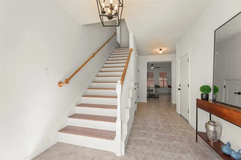 a view of a hallway to a livingroom with wooden floor and stairs