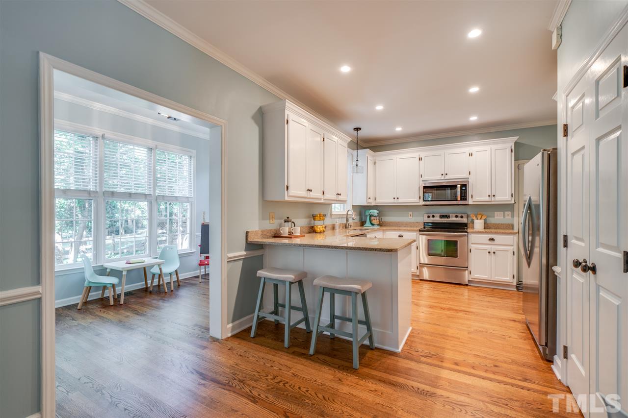 2101 Fountain Ridge Road Chapel Hill, NC 27517 - Photo 5 of 30 a kitchen with stainless steel appliances granite countertop a stove top oven a refrigerator a sink and white cabinets with wooden floor