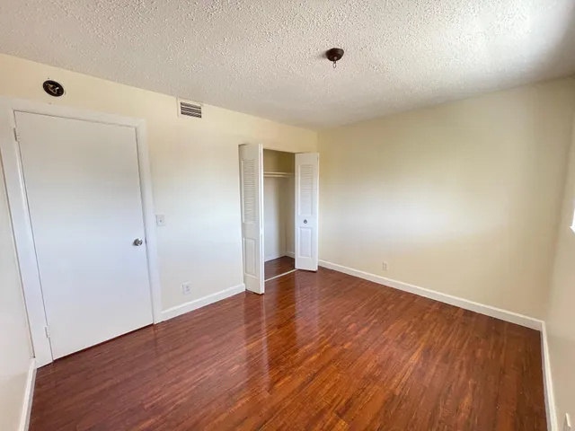 an empty room with wooden floor and fan