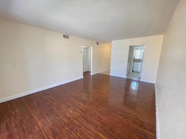 a view of an empty room with wooden floor and a window