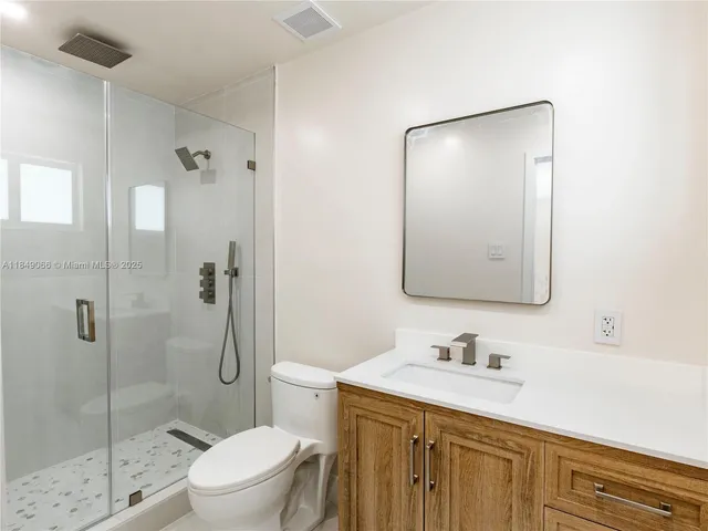 a bathroom with a granite countertop sink a toilet and shower