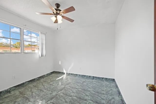 an empty room with windows and fan