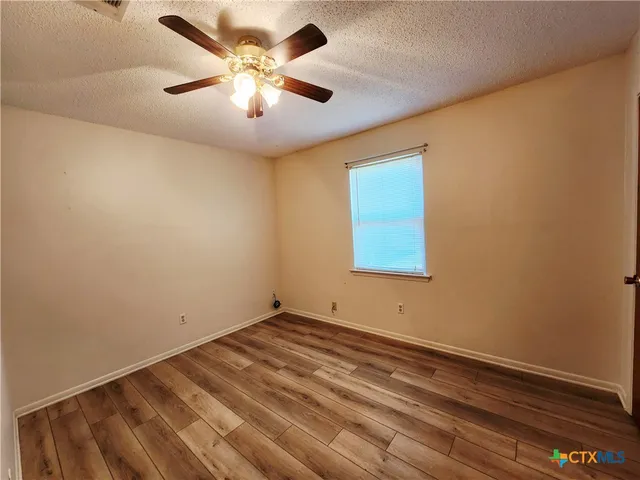 an empty room with a window and a ceiling fan