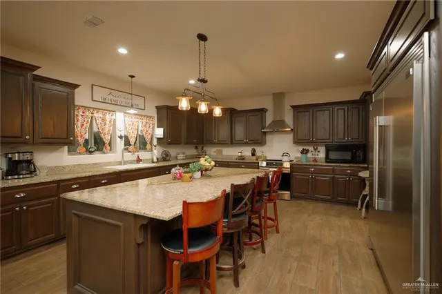 a kitchen with stainless steel appliances kitchen island granite countertop a sink a stove a dining table and chairs