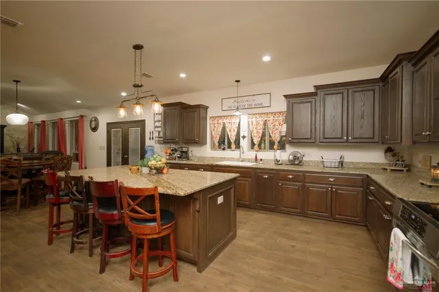 a kitchen with stainless steel appliances granite countertop a table chairs sink and cabinets