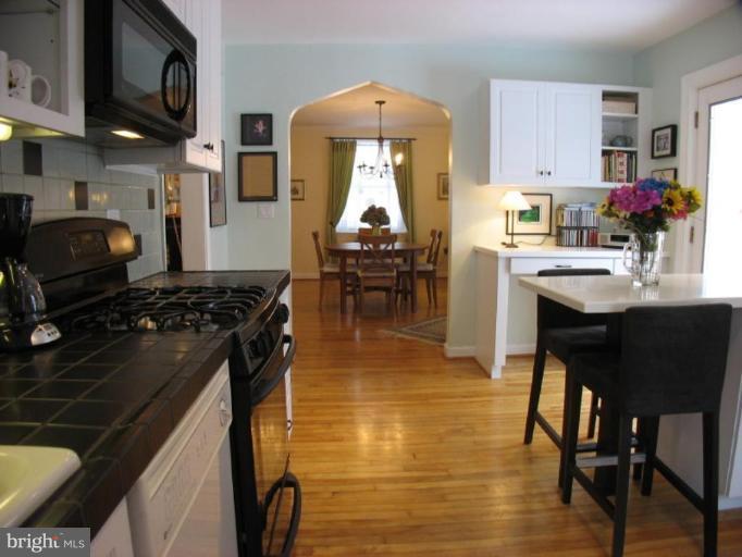 605 Deepdene Road Baltimore, MD 21210 - Photo 16 of 30 a kitchen with stainless steel appliances granite countertop a stove a sink dishwasher a dining table and chair with wooden floor