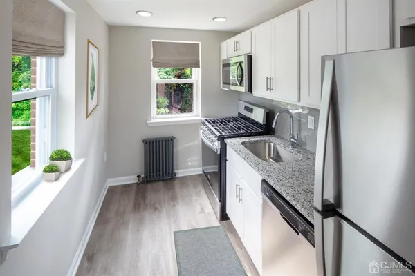 a kitchen with granite countertop stainless steel appliances a sink window and cabinets