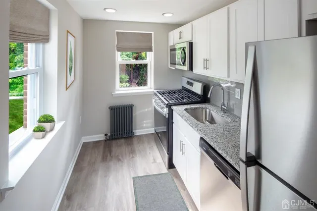 a kitchen with granite countertop stainless steel appliances a sink window and cabinets